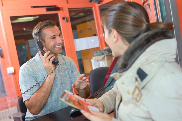 Vrouw op ticket booth, leverancier op telefoon — Stockfoto