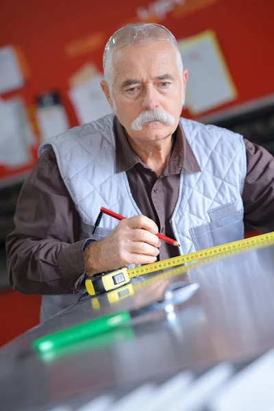 Senior carpenter measures wooden plank — Stock Photo, Image