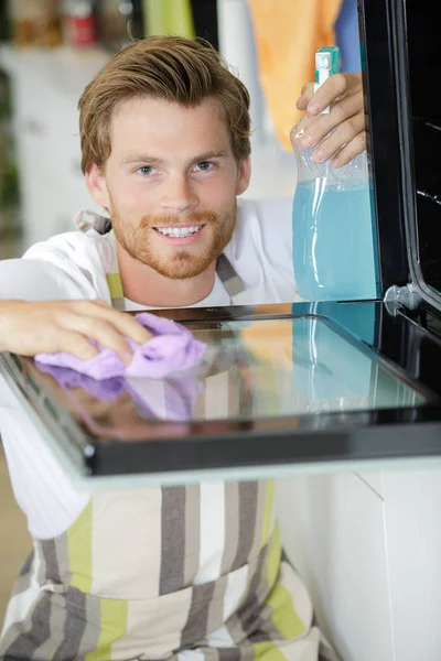 Man cleaning oven and person — Stock Photo, Image
