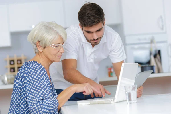 Junger Mann hilft Dame mit ihrem Computer — Stockfoto