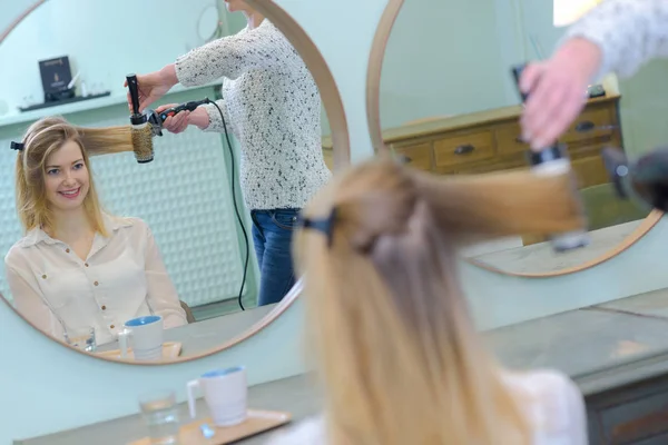 Cabelo de secagem estilista de cliente feminino jovem — Fotografia de Stock