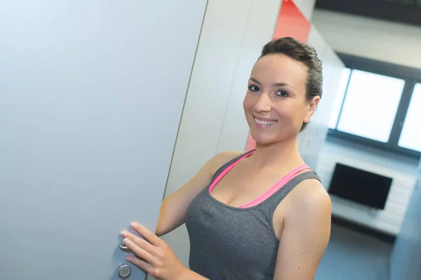 Lachende vrouw klaar voor een training in de sportschool kleedkamer — Stockfoto