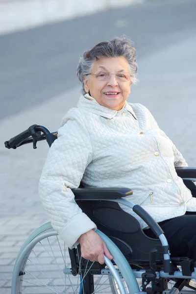 Gammal kvinna på den rullstol leende — Stockfoto