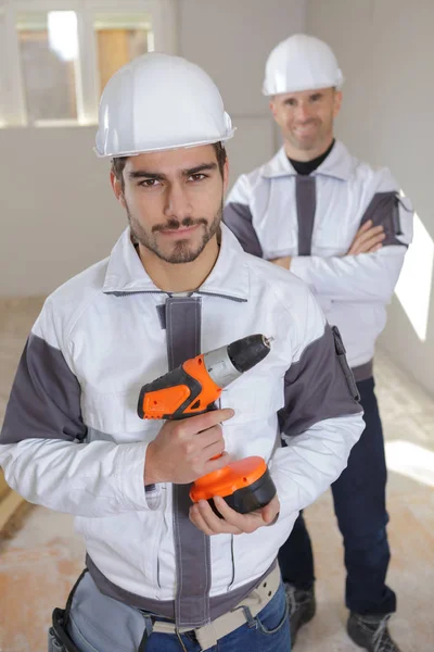 Barba sonriente hombre con taladro en el sitio de construcción —  Fotos de Stock