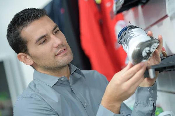 Schöner Mann schaut auf Schuhe im Sportgeschäft — Stockfoto