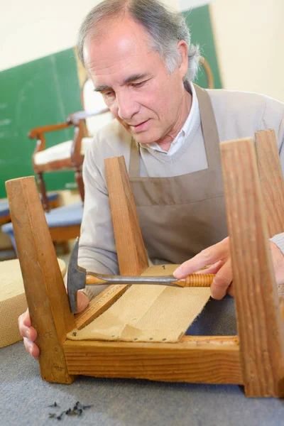 Mann polstert Stuhl in seiner Werkstatt — Stockfoto