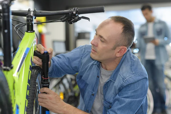 Člověk kontroluje kolo před nákupem v prodejně sport — Stock fotografie