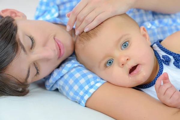 Glad mamma med barnet ligger på sängen hemma — Stockfoto