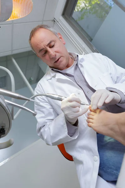 Mature podologist curing patients foot — Stock Photo, Image