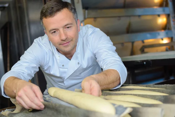 Stolzer Bäcker backt Baguettebrot in seiner Küche — Stockfoto