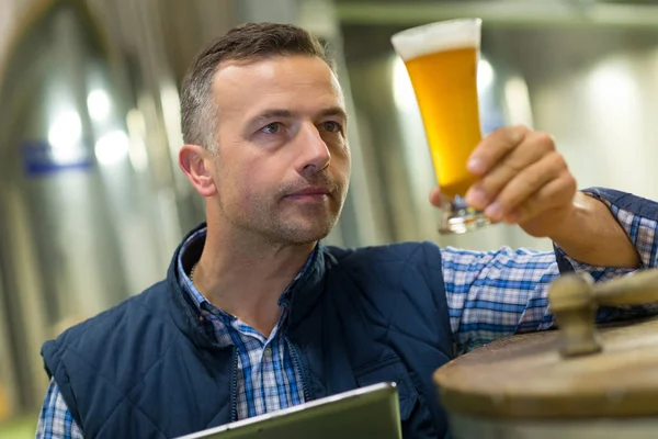 Cervecero guapo en uniforme degustación de cerveza en la cervecería —  Fotos de Stock