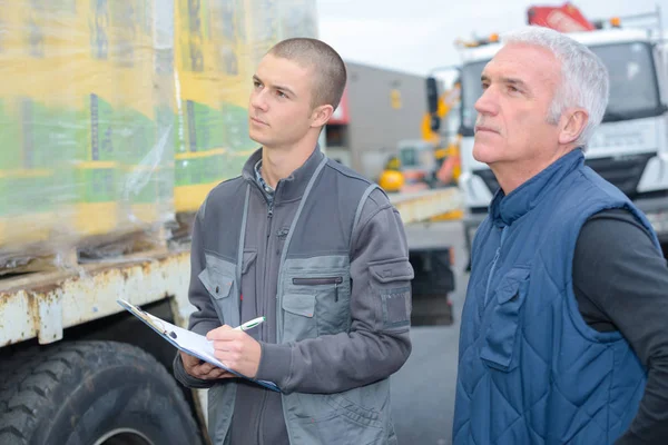 Man with clipboard looking at delivery on lorry — Stock Photo, Image