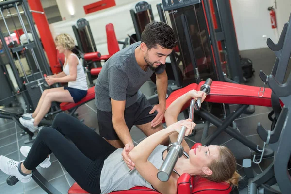 Entrenador y mujer haciendo ejercicio en el gimnasio — Foto de Stock