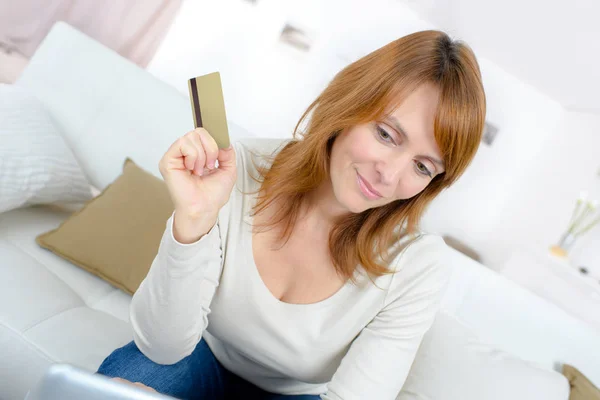 Beautiful mature woman holding a credit card to shop online Stock Picture