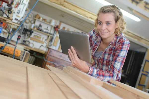 Woman using tab and looking at wooden planks — Stock Photo, Image