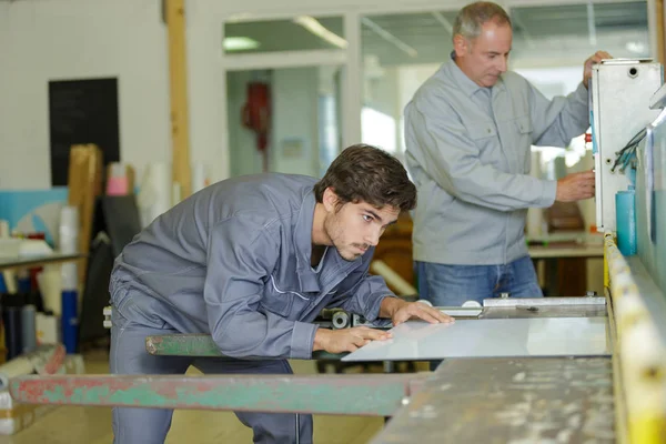 Trabalhadores manuais do sexo masculino examinando chapas metálicas na indústria — Fotografia de Stock