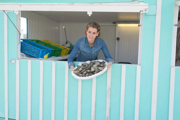 Young woman holding an oyster tray outside her shop — Stock Photo, Image