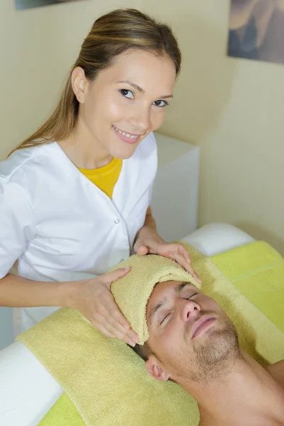 Female worker treating a male customer in salon — Stock Photo, Image