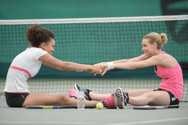 Dos atractivas jugadoras de tenis estirándose en la cancha — Foto de Stock