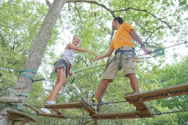 Jovem casal se divertindo em uma ponte de corda — Fotografia de Stock