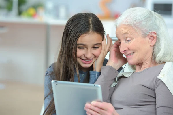 Mormor ser på tablett med barnbarn — Stockfoto