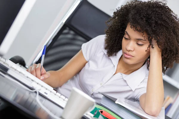 Joven empresaria sentada en el lugar de trabajo y leyendo papel en la oficina —  Fotos de Stock