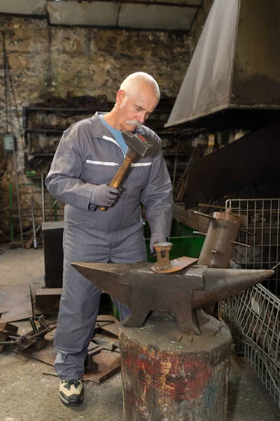 ハンマーのアンビルを使ったシニア男性鍛冶屋 — ストック写真