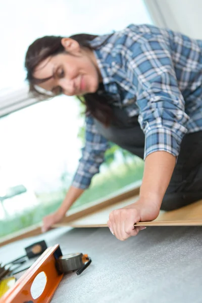 Trabalhador feminino colocando piso de madeira — Fotografia de Stock