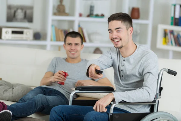 Cheerful disabled young man watching tv with friend — Stock Photo, Image
