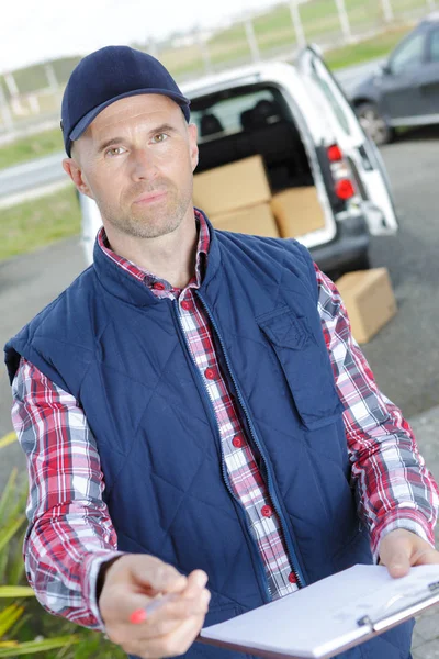 Ein hübscher junger Zusteller, der ein Paket ausliefert — Stockfoto