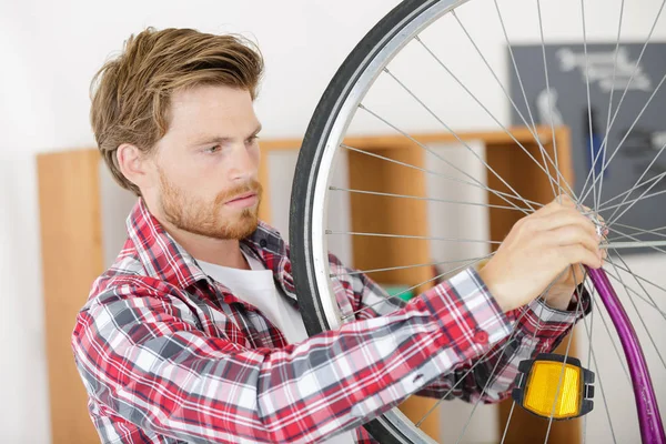 Man tot vaststelling van een fiets boven de grijze achtergrond — Stockfoto