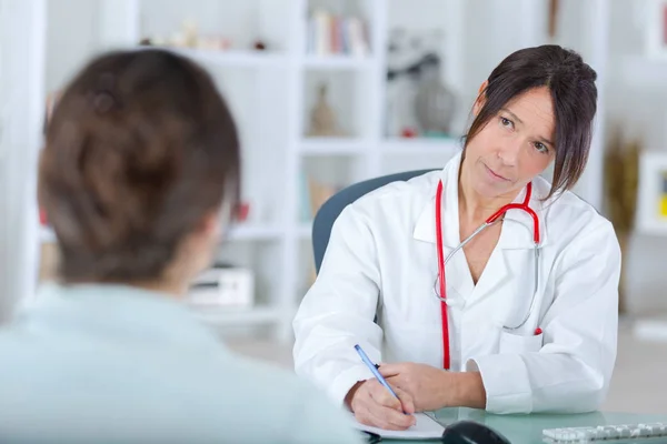 Femme médecin écoute son patientin bureau — Photo