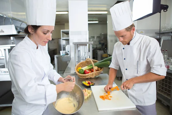 Chefs felizes e assistente em avental trabalhando na cozinha do restaurante — Fotografia de Stock