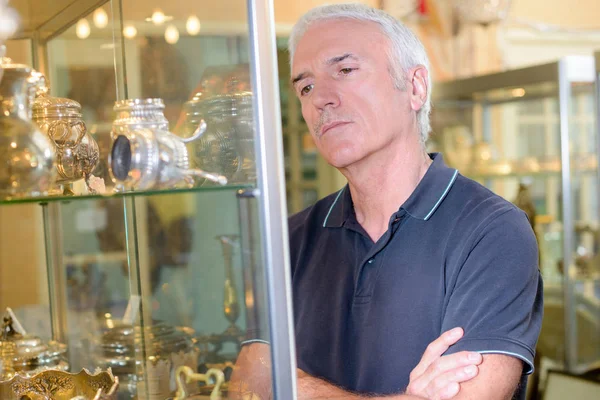 Senior man staren naar objecten in de glazen kast — Stockfoto