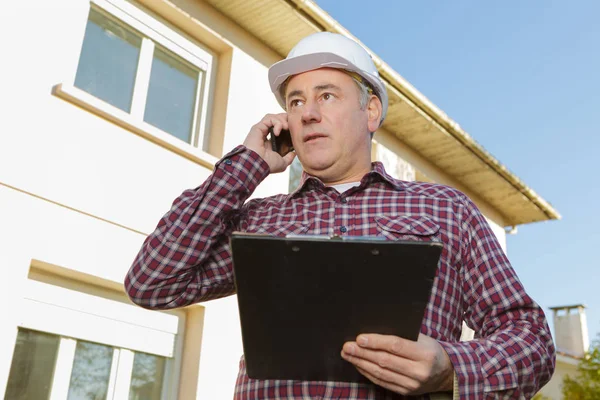 Architect on building site using mobile phone — Stock Photo, Image