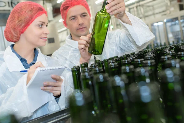 2 coleagues working on bottling factory line — Stock Photo, Image