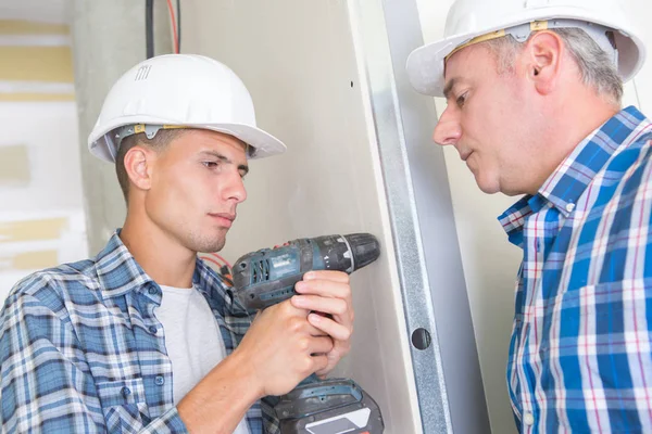 Jonge man met boormachine op muur thuis — Stockfoto