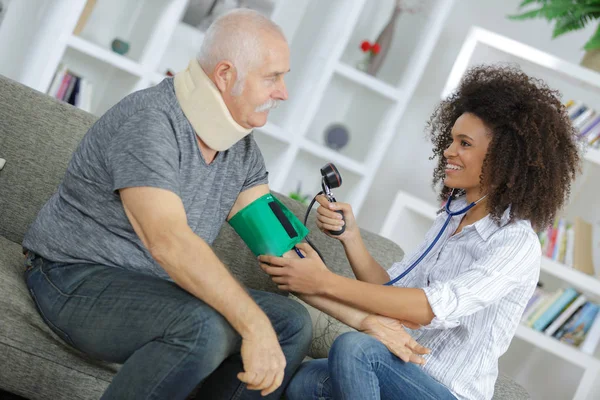 Verpleegkundige examencommissie bloeddruk van senior man thuis — Stockfoto