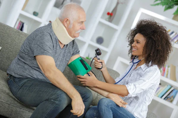 Enfermera examinando la presión arterial del hombre mayor en casa —  Fotos de Stock