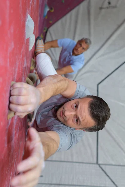 Jeune homme escalade mur intérieur et atteindre le sommet — Photo