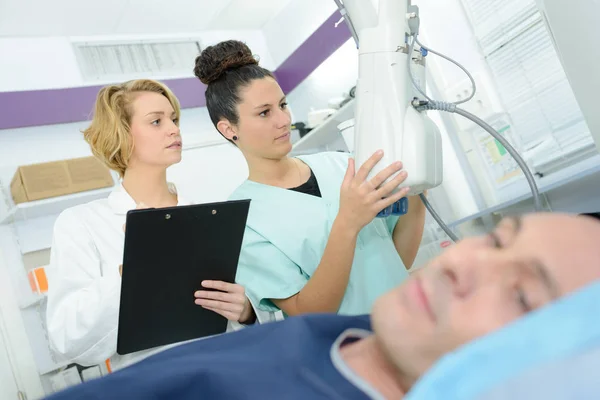 Kvinnliga läkare och assistent pågående tentamen på patient — Stockfoto