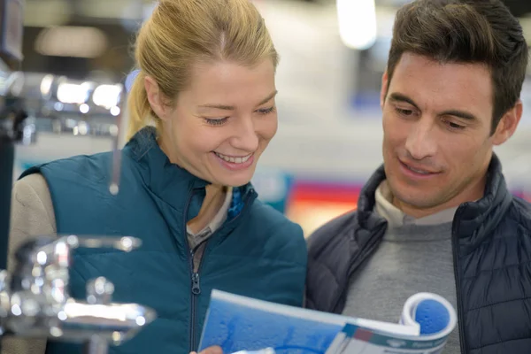 Young woman in overalls assisting a customer — Stock Photo, Image