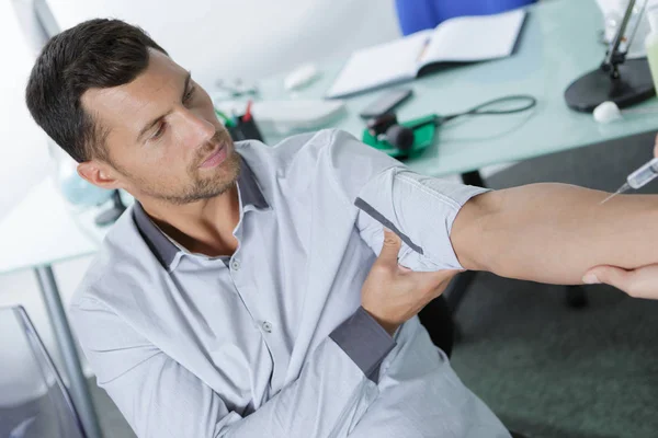 Hombre con problemas para recibir la inyección en la clínica — Foto de Stock