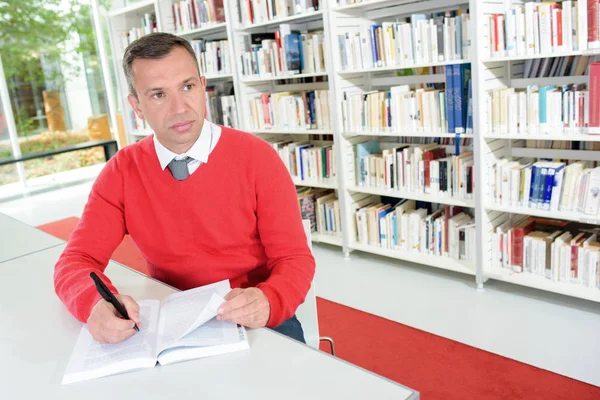 Mannen att göra anteckningar i biblioteket — Stockfoto