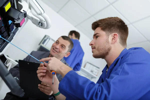 Young apprentice technician fixing office photocopier — Stock Photo, Image