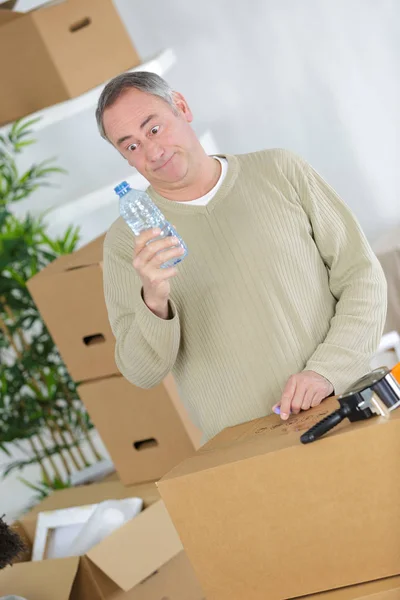 Müder Mann mit Pappkartons trinkt Wasser — Stockfoto