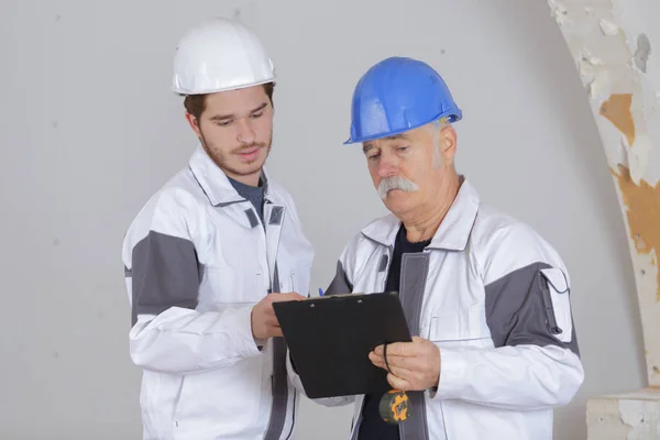Builder och inspektör tittar en oavslutad boende — Stockfoto