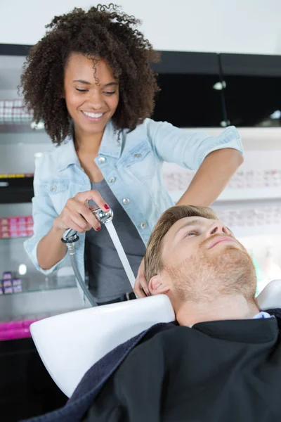 Парикмахер сушит волосы клиентов мужского пола в салоне — стоковое фото