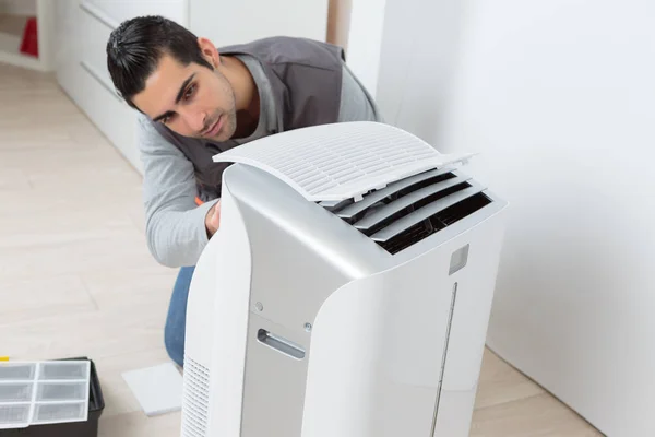 Happy male technician repairing air conditioner — Stock Photo, Image