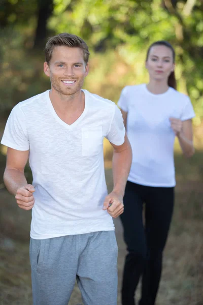 Красивая молодая пара, бегающая вместе в парке — стоковое фото